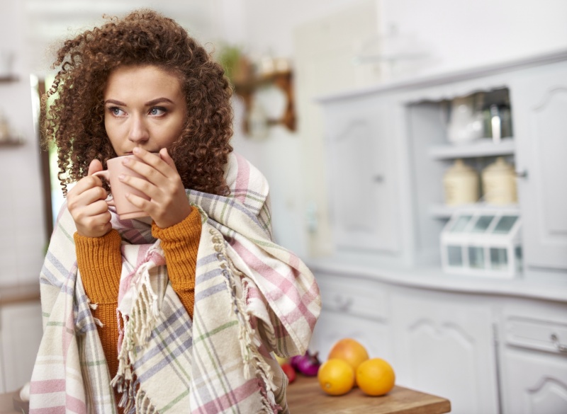 woman-huddled-in-blanket-drinking-out-of-mug